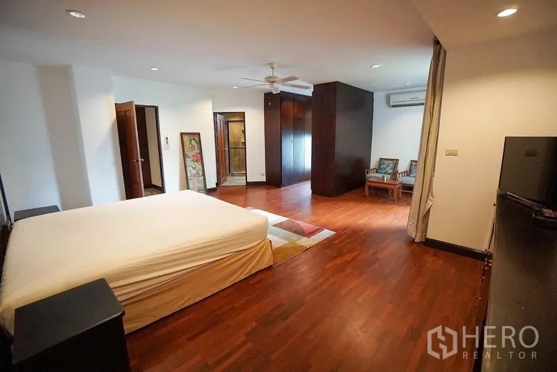 房间 出租在Watthana, Bangkok - 宽大的主卧，木地板、休闲角与衣柜。