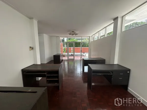 带办公室的家 出租在Watthana, Bangkok - 细长工作区通向玻璃门外的前庭，沿墙摆放深色书桌。