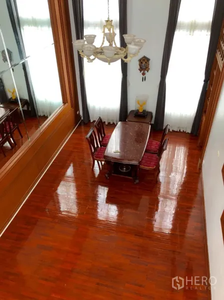 Townhouse for rent in Khlong Toei, Bangkok - Double-height dining space with chandelier, tall draped windows and polished hardwood floors.