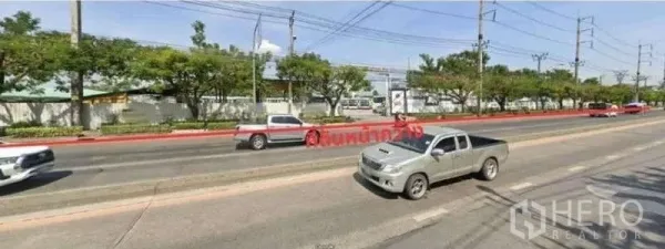 Land for rent in Suan Luang, Bangkok - Wide multi-lane road with trees and power lines along the site frontage, indicating easy access and high visibility.