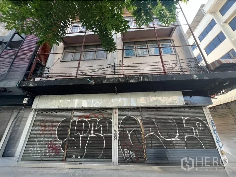 Shophouse for rent in Khlong Toei, Bangkok - Street-facing shophouse facade with rolling shutters and upper balconies.