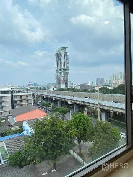 公寓 出售 - 窗外景观，可见高架道路、绿化与曼谷天际线。