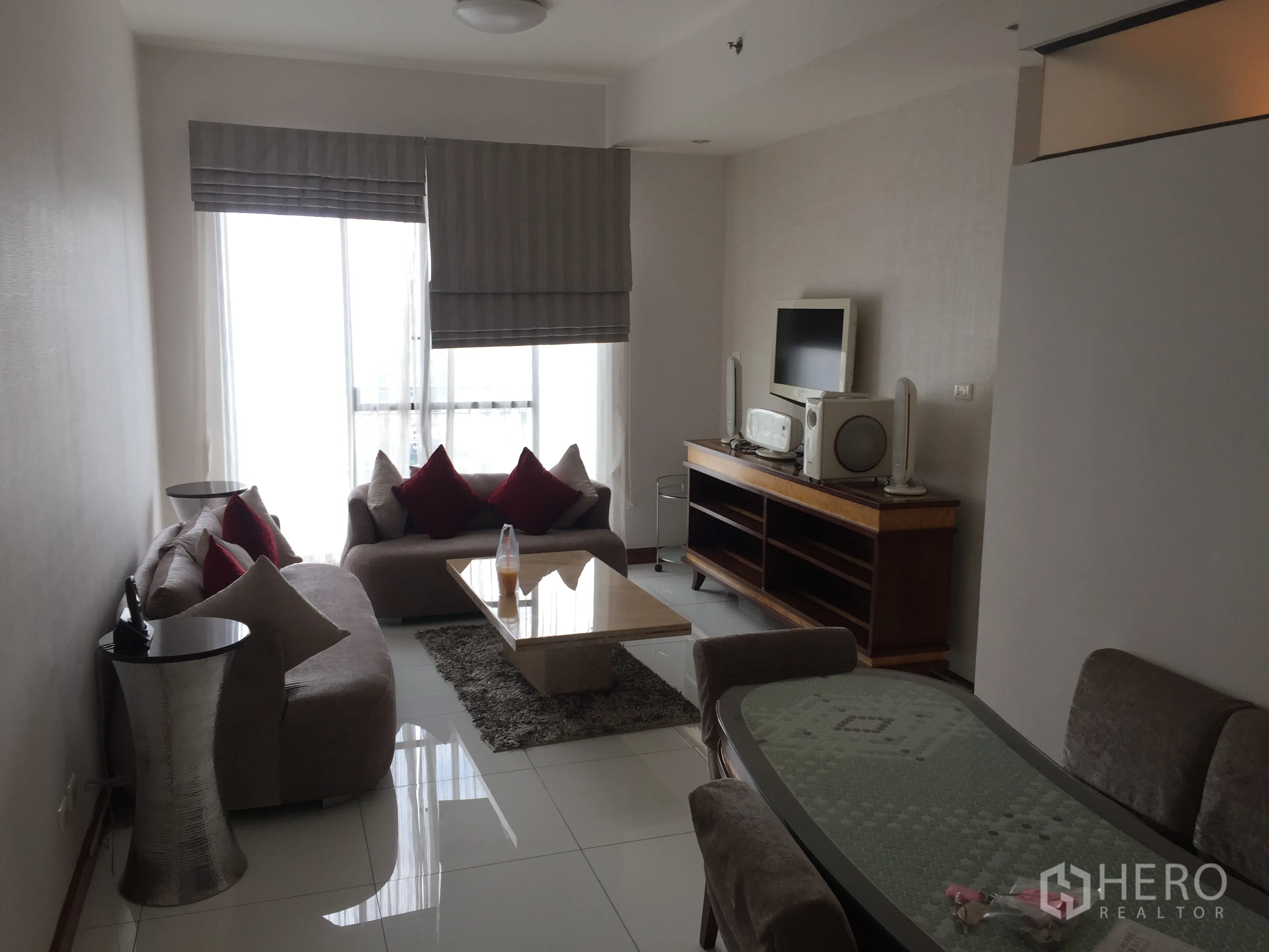Condominium for rent in Watthana, Bangkok - Bright living room with sofas, coffee table and TV console beside a large window.