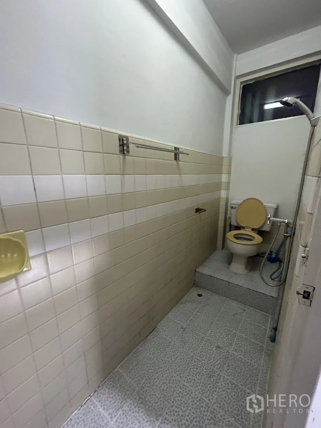 Shophouse for rent in Khlong Toei, Bangkok - Narrow bathroom with raised toilet platform and handheld shower.