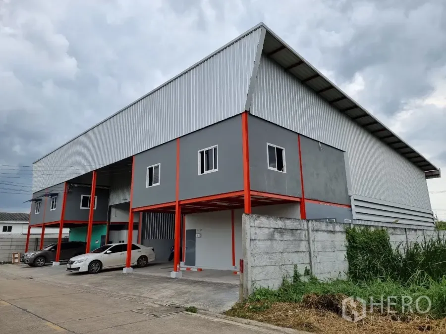 Warehouse for rent in Lam Luk Ka, Pathum Thani - Modern warehouse exterior with grey facade, red steel columns and covered parking in Lam Luk Ka.