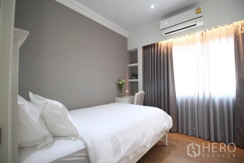 独立式住宅 出租或出售在Lat Phrao, Bangkok - 次卧配双人床，灰色强调墙与窗边小书桌。