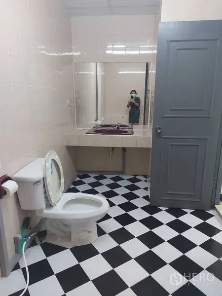 Office Space for rent in Pathum Wan, Bangkok - Restroom with black-and-white checkered floor, toilet and a long vanity with a large wall mirror.