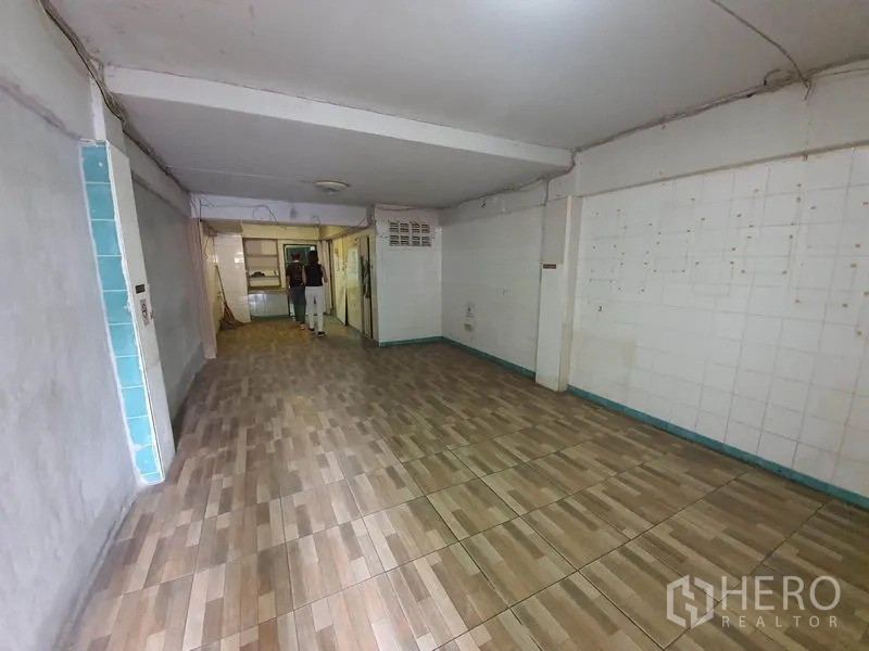 店屋 出租在Bang Rak, Bangkok - 一层临街营业空间，木纹地砖、白色墙面，深进式布局通向玻璃隔间。