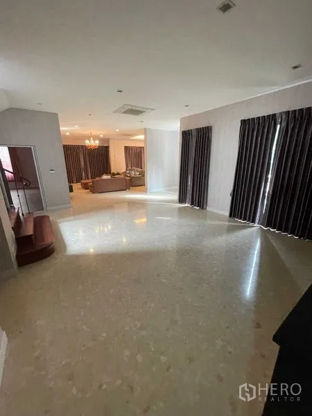 独立式住宅 出售在Mueang Samut Prakan, Samut Prakan - 开阔起居大厅，石材地面、深色窗帘与休息区视角