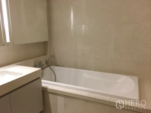 公寓 出租在Watthana, Bangkok - 米色石材墙面的浴室，内置浴缸与手持花洒。