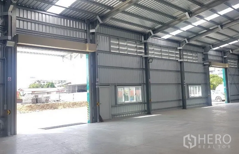 Warehouse for rent in Mueang Nonthaburi, Nonthaburi - Multiple loading bay doors and windows along the side wall for ventilation and access.