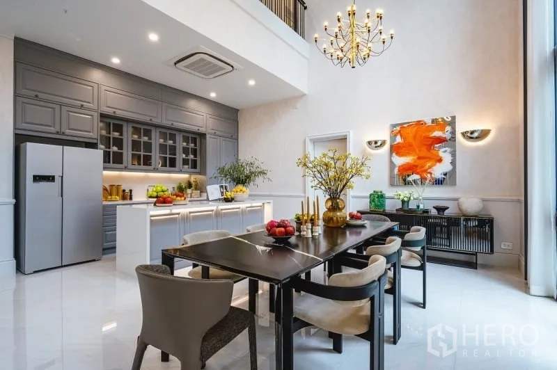 Detached House for sale in Bang Kapi, Bangkok - Gourmet kitchen and dining area with island, gray cabinetry and chandelier under a double-height ceiling.