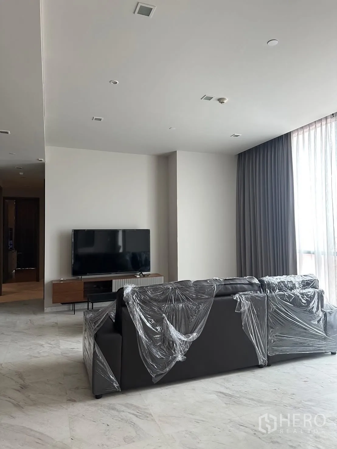 Condominium for rent or sale in Watthana, Bangkok - Lounge facing TV with sectional sofa wrapped for move-in.