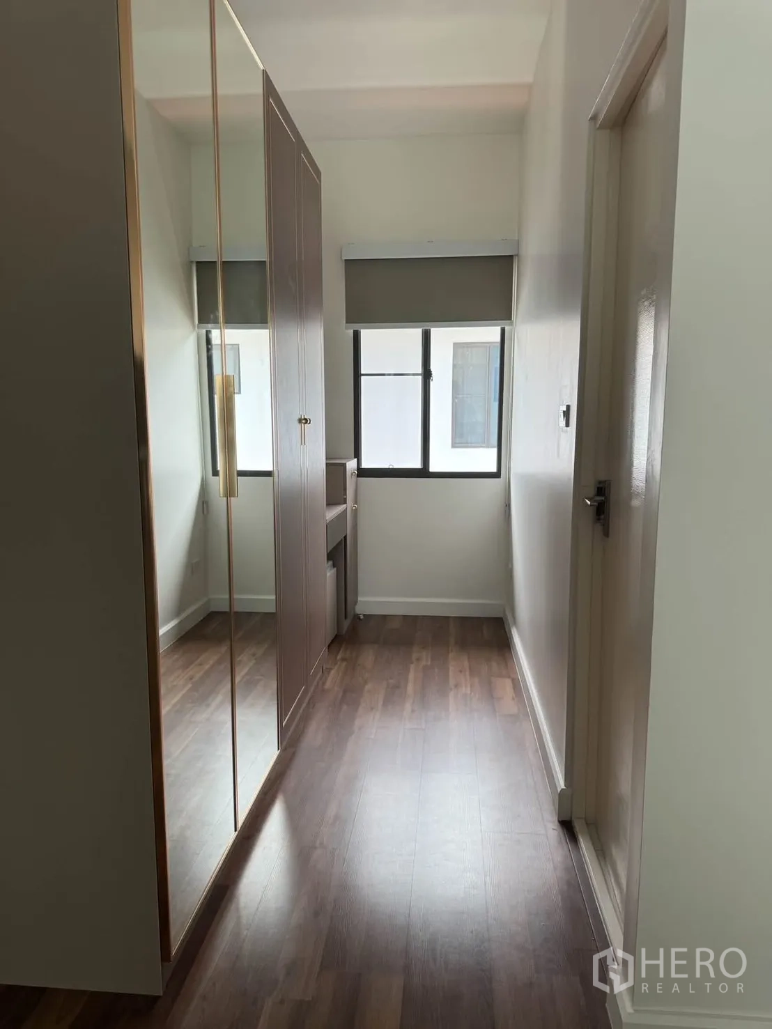 Detached House for rent in Prawet, Bangkok - Walk-in closet corridor with mirrored wardrobe doors and a dressing table.