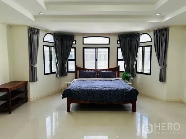 Home Office for rent in Watthana, Bangkok - Large master bedroom with arched windows, ceiling spotlights, and neutral tile flooring.