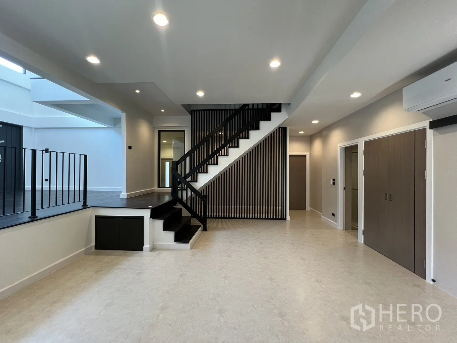 Detached House for rent in Saphan Sung, Bangkok - Open-plan living area with split-level floor, black staircase and vertical wood slat feature wall.