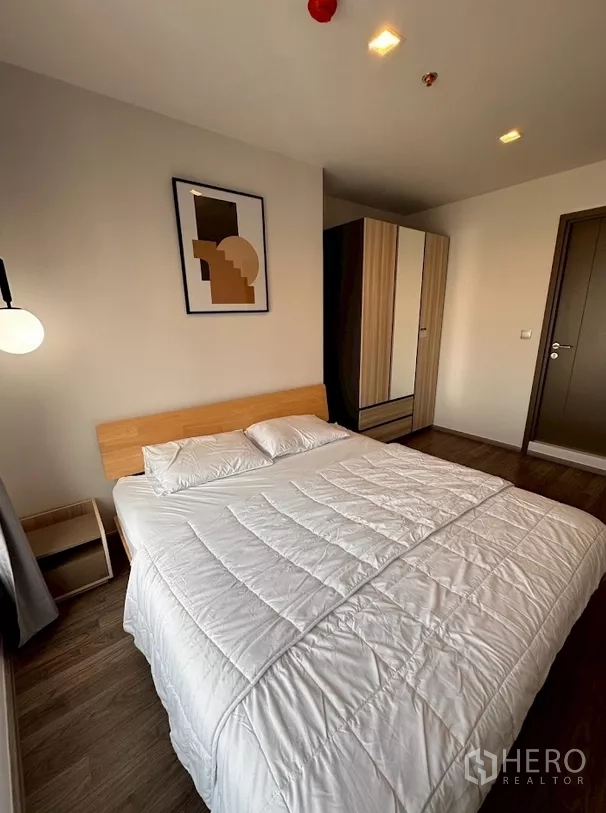 公寓 出租在Chatuchak, Bangkok - 卧室内白色床品、衣柜与通往走廊的房门。