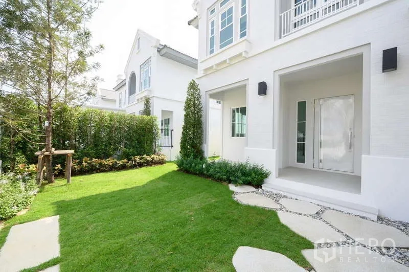 Detached House for rent or sale in Bang Phli, Samut Prakan - Front garden with stepping-stone path, shrubs and a covered porch of the house.