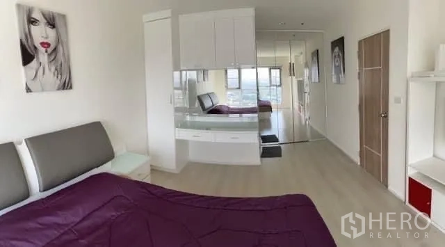 Condominium for sale in Khlong Toei, Bangkok - Spacious bedroom with built-in dresser, mirror wardrobes and a city view.