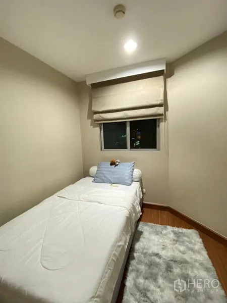 คอนโด ให้เช่า - ห้องนอนเล็ก เตียงเดี่ยว หน้าต่างเห็นวิวเมือง และพรมฟู