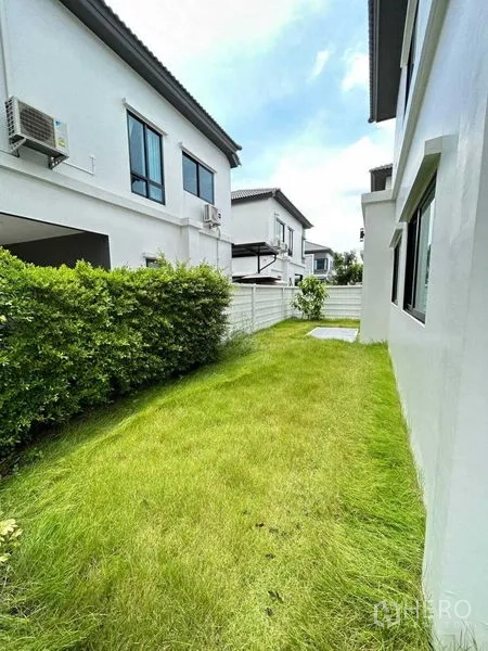 独立式住宅 出租在Khlong Sam Wa, Bangkok - 侧院草坪，绿篱与白色围栏