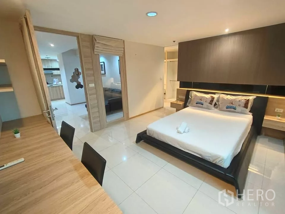 Condominium for rent in Khlong Toei, Bangkok - Spacious master suite showing work desk, bed, and doorway to the living area.