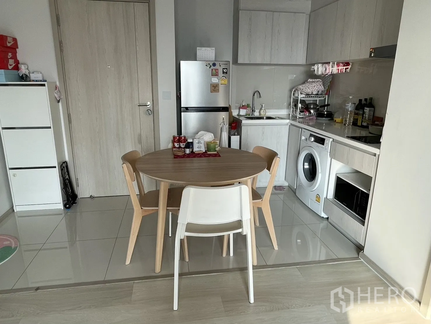 公寓 for rent in Pathum Wan, Bangkok - 厨房与餐区，圆形木桌、冰箱、白色橱柜并集成洗衣机。