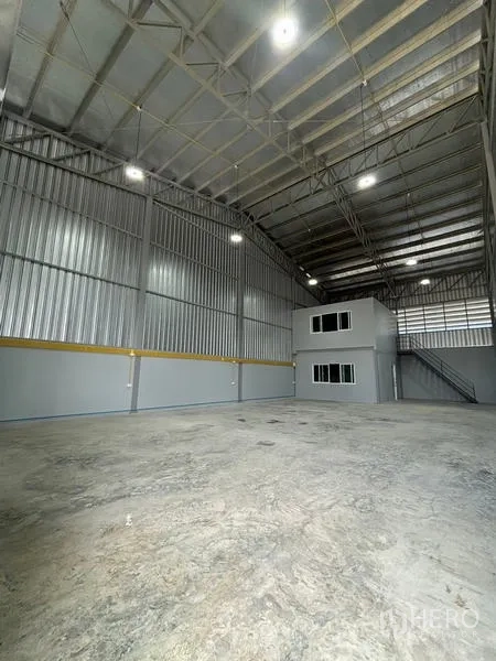 Warehouse for rent in Mueang Pathum Thani, Pathum Thani - Spacious warehouse interior with high clear-span roof, concrete floor and a two-storey office box with stairs.