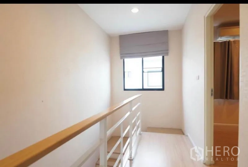 联排别墅 出租或出售在Wang Thonglang, Bangkok - 明亮的楼梯平台，设窗户、浅木色扶手并通往卧室。