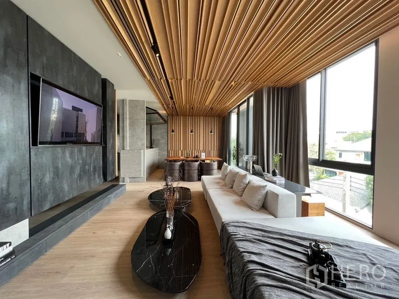 带办公室的家 出售在Prawet, Bangkok - 时尚客厅，木格栅吊顶、大型沙发与黑色大理石茶几。