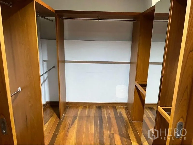 Townhouse for sale in Phra Khanong, Bangkok - Large walk-in closet with open wooden wardrobes, shelving, and mirror.