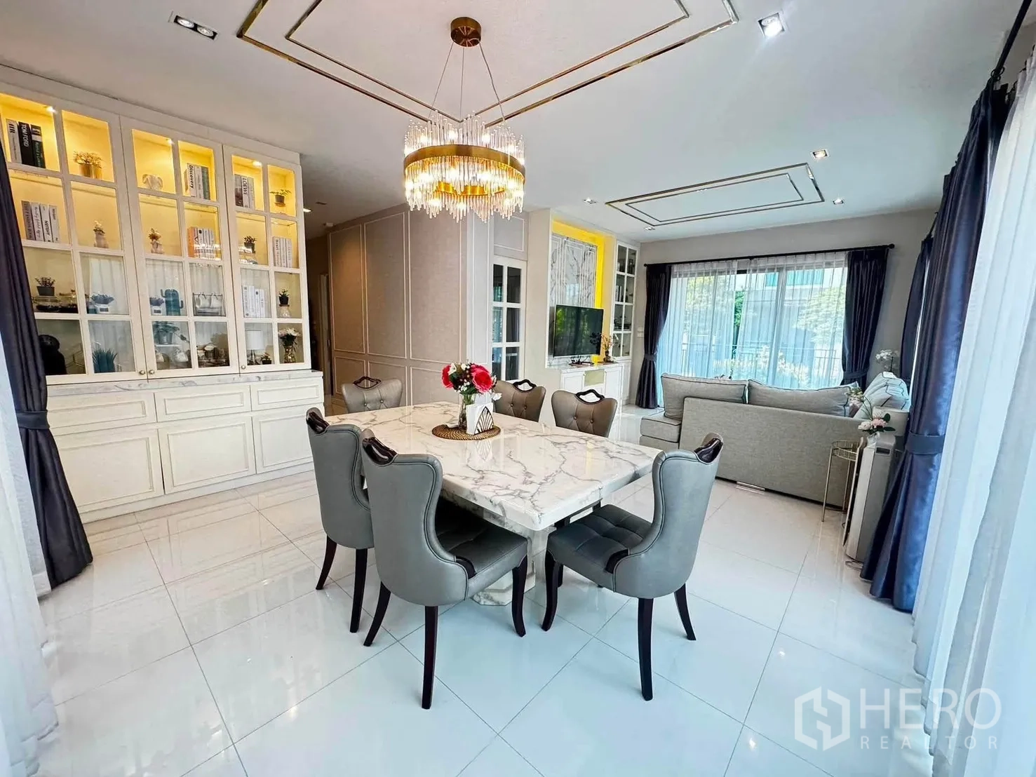 Detached House for rent in Saphan Sung, Bangkok - Dining area with marble-top table, six chairs, chandelier, and illuminated display cabinet.