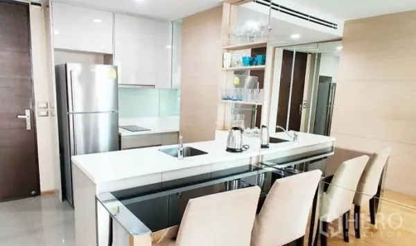 Condominium for rent in Ratchathewi, Bangkok - Open‑plan kitchen with white cabinets, long breakfast bar, stainless refrigerator and dining chairs.