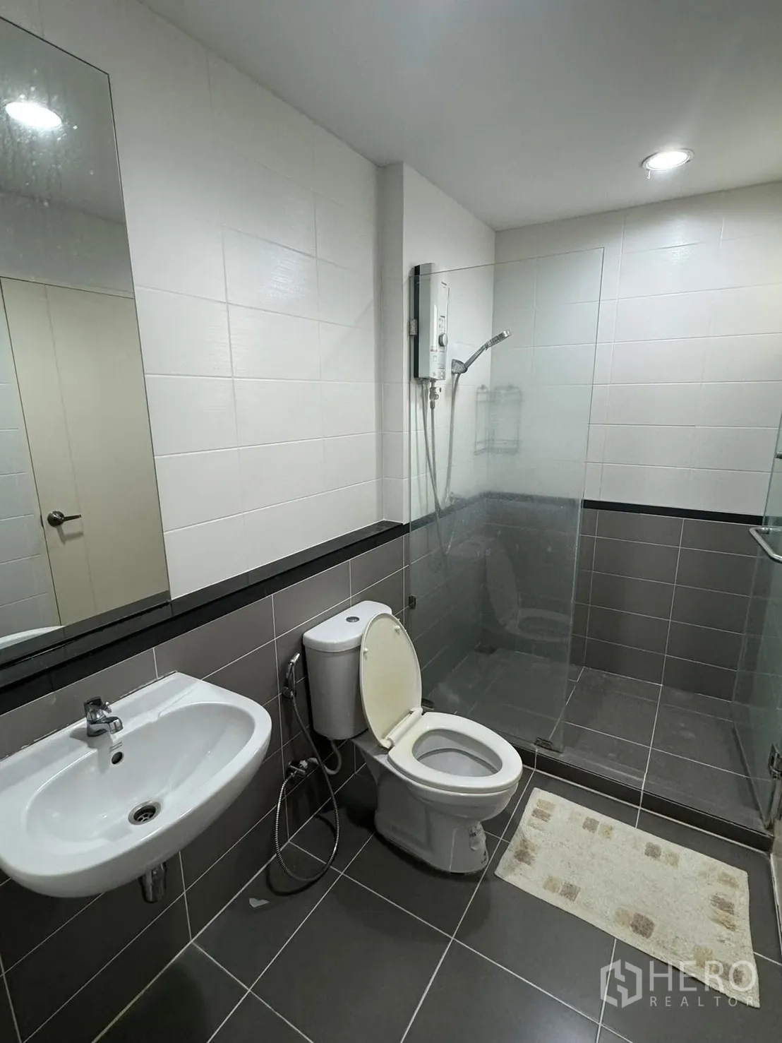 Townhouse for rent in Suan Luang, Bangkok - Contemporary bathroom with glass-enclosed shower, toilet and large mirror.
