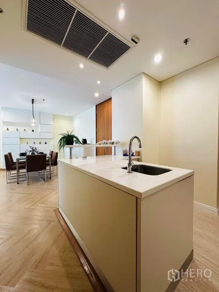 Condominium for rent in Bang Rak, Bangkok - Open-plan kitchen with island sink facing the dining area and built-in shelving.