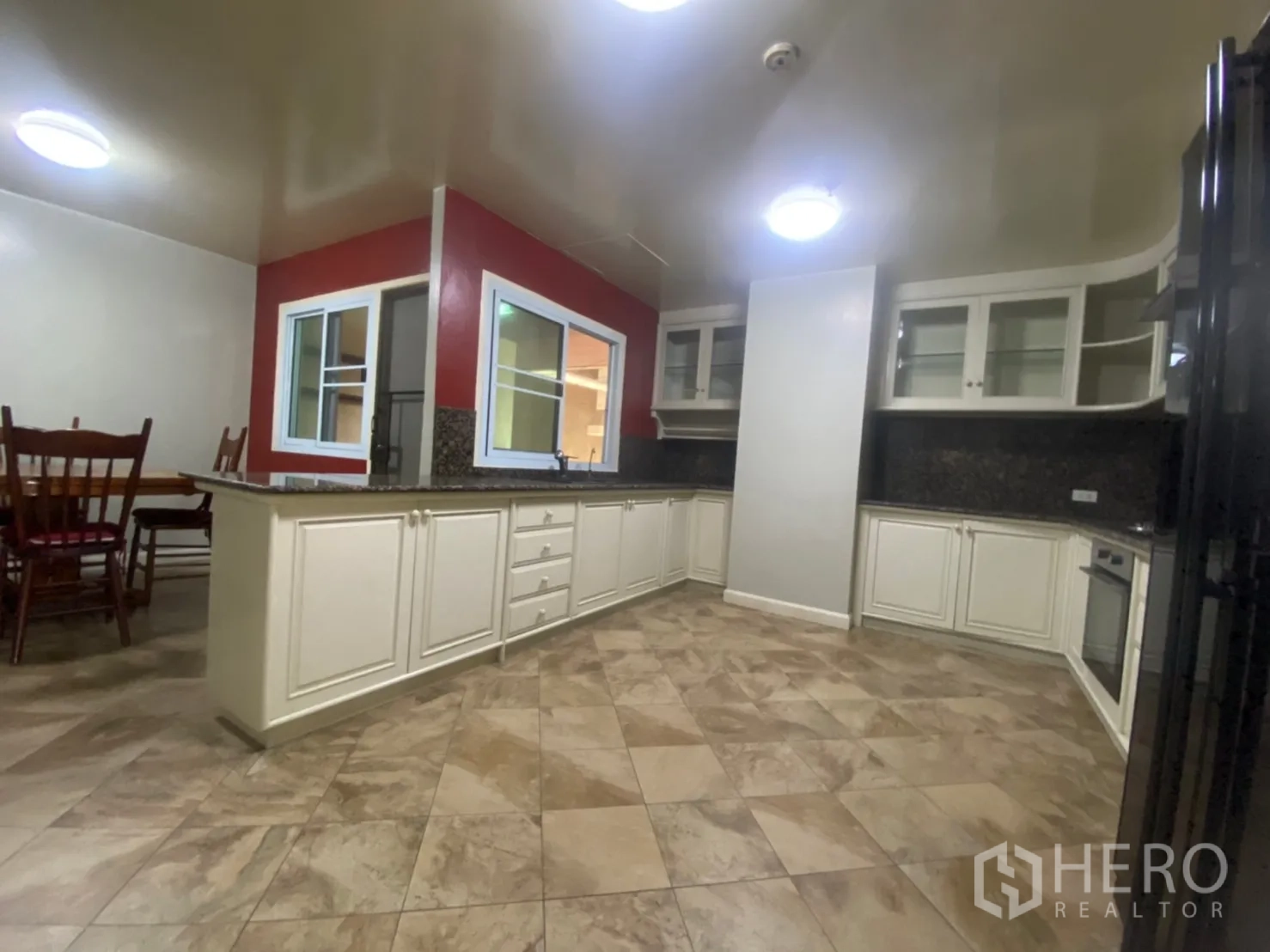 Condominium for rent or sale in Watthana, Bangkok - Separate kitchen with white cabinetry, granite counters, built-in oven and a red accent wall.