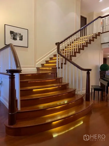 Condominium for rent or sale in Watthana, Bangkok - Curved wooden staircase with warm step lighting and white balustrade.