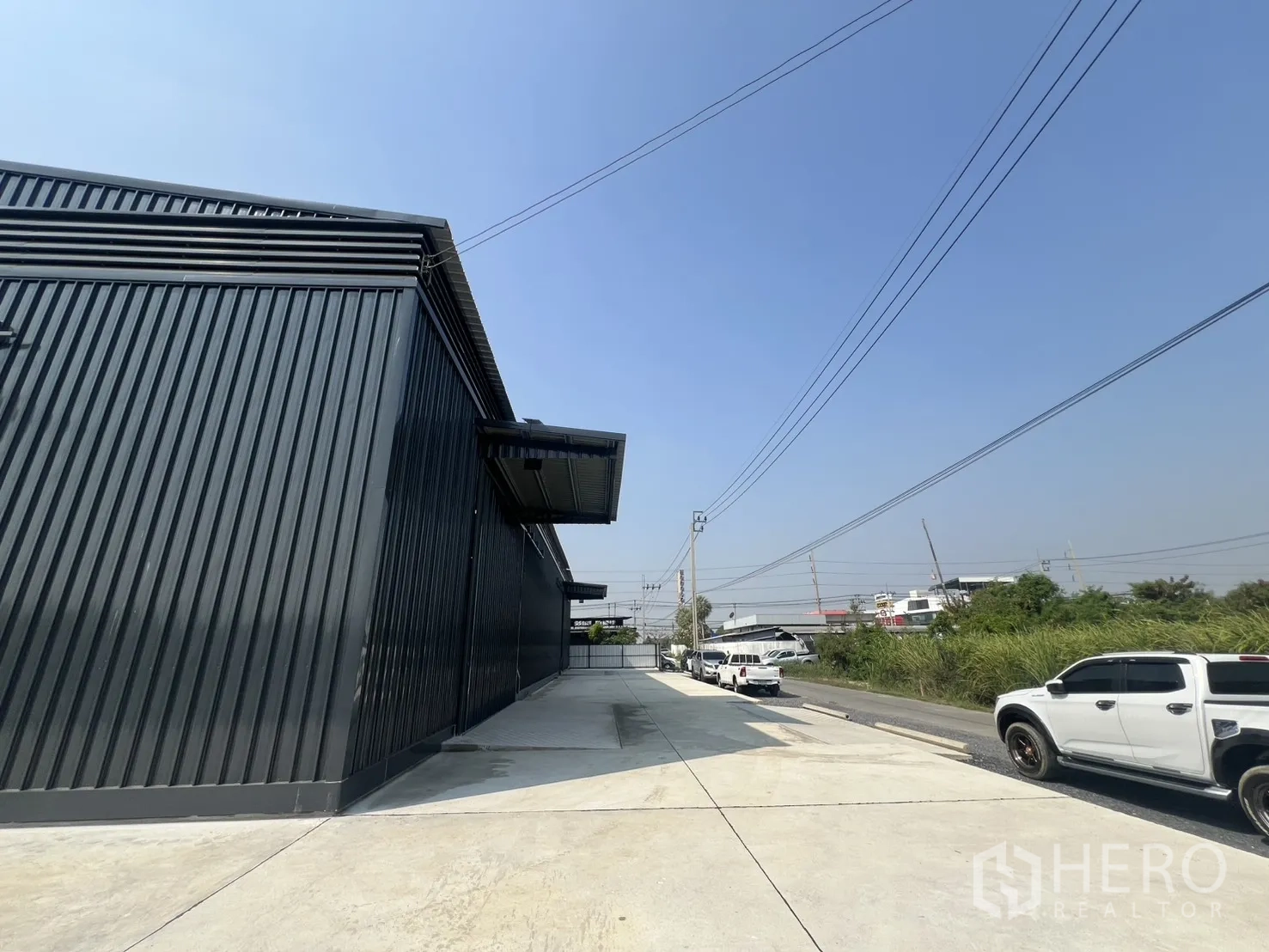 货栈 出租在Lat Krabang, Bangkok - 仓库外的通行道路与停车区，配有开阔院场与架空电线。