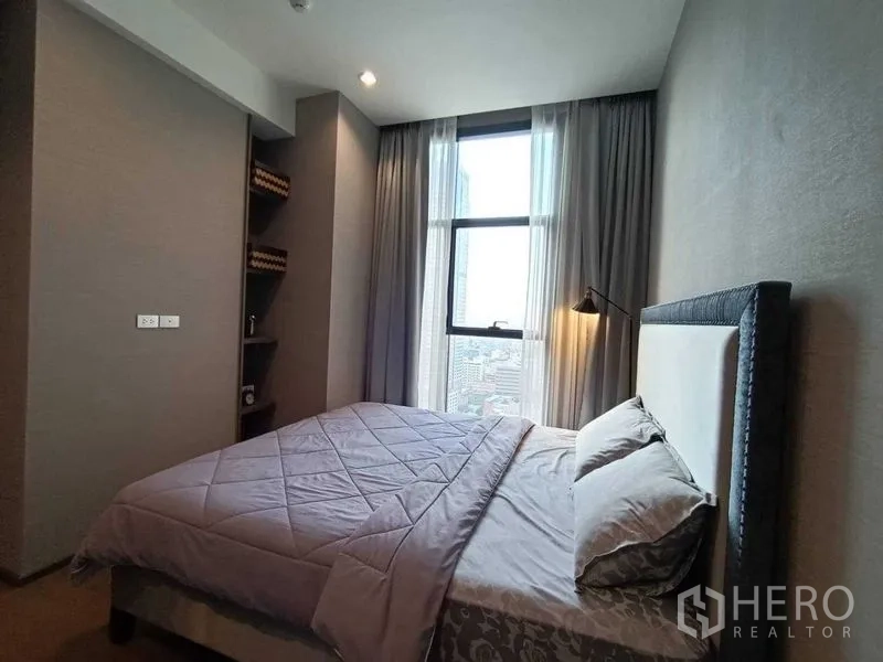 Condominium for rent or sale in Bang Rak, Bangkok - Cozy bedroom with double bed, tall window, sheer curtains and city view.