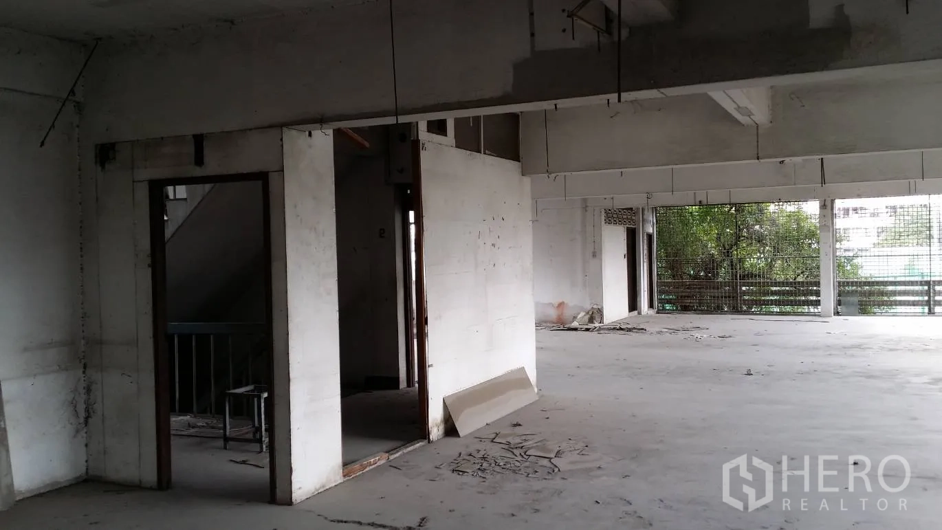 Office Space for rent in Don Mueang, Bangkok - Raw open‑plan office floor with concrete surfaces, exposed beams and large grilled windows in Don Mueang, Bangkok.