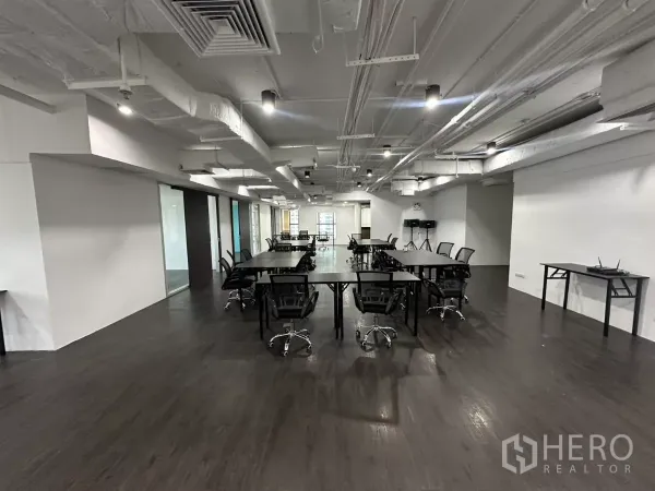 Office Space for rent in Watthana, Bangkok - Long workspace with rows of desks, glass-partitioned rooms and bright ceiling lights.