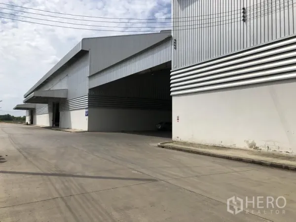 Factory for rent in Wang Noi, Phra Nakhon Si Ayutthaya - Corner view of an expansive warehouse block with wide canopy and broad concrete road.