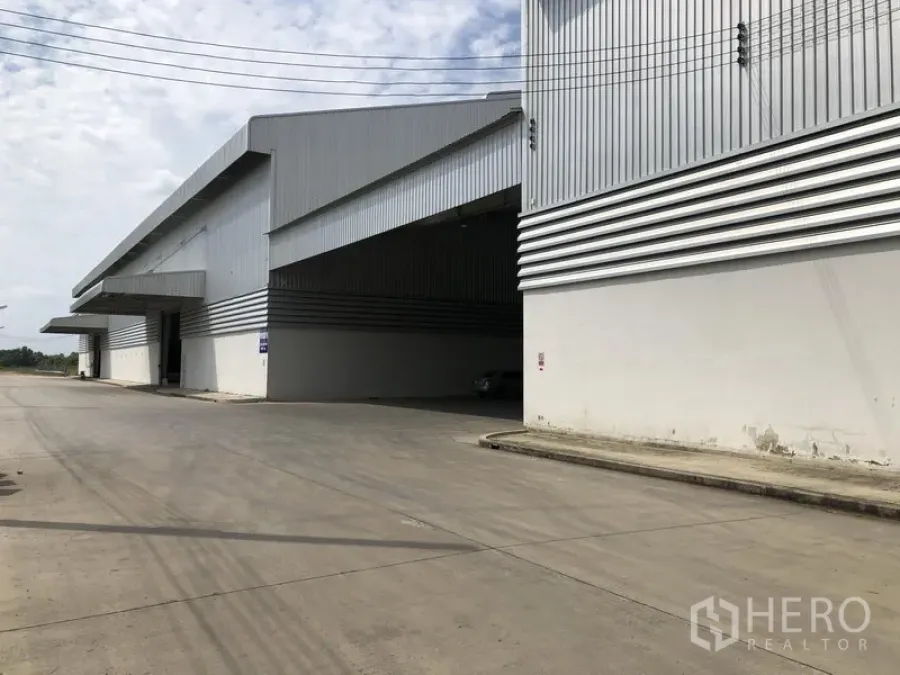 Factory for rent in Wang Noi, Phra Nakhon Si Ayutthaya - Corner view of an expansive warehouse block with wide canopy and broad concrete road.