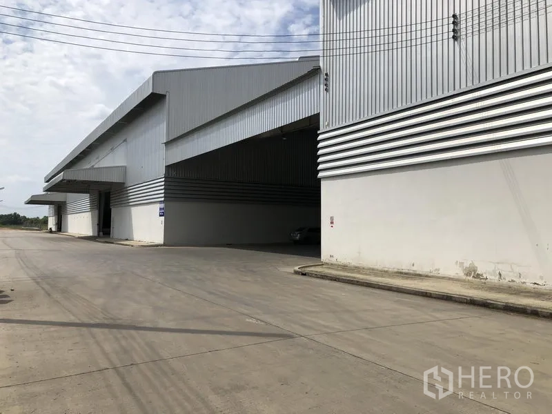Factory for rent in Wang Noi, Phra Nakhon Si Ayutthaya - Corner view of an expansive warehouse block with wide canopy and broad concrete road.