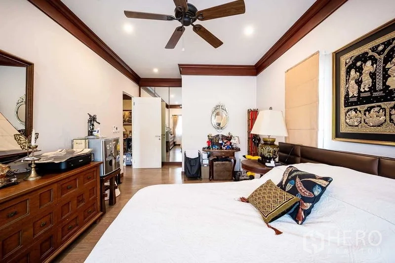 独立式住宅 出售在Prawet, Bangkok - 卧室内置吊扇与木质家具，墙上装饰画。