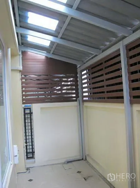 联排别墅 出租或出售在Wang Thonglang, Bangkok - 带金属顶棚的后勤或侧院空间，木格栅围栏保障私密。