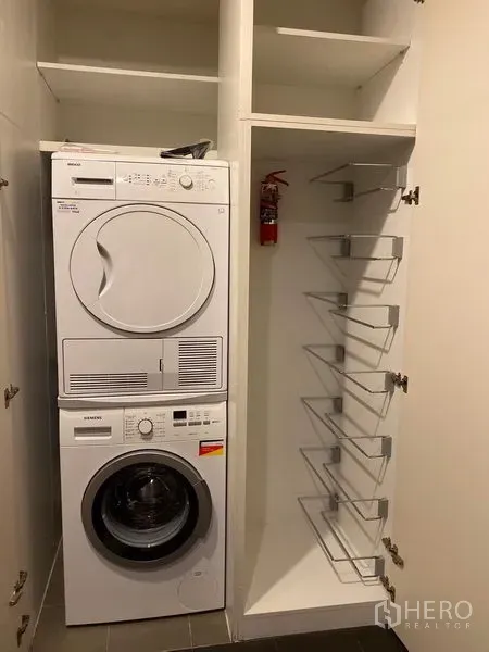 Condominium for rent in Khlong Toei, Bangkok - Laundry closet featuring stacked washer and dryer with built-in storage racks.