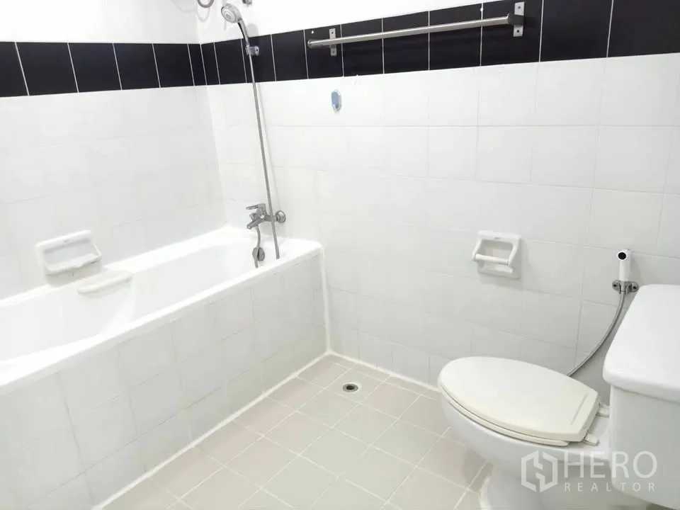 Condominium for rent in Watthana, Bangkok - White-tiled bathroom with bathtub, handheld shower, and toilet.
