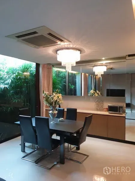 独立式住宅 出售在Watthana, Bangkok - 餐厅配水晶吊灯与镜面墙，可眺望绿意庭院。