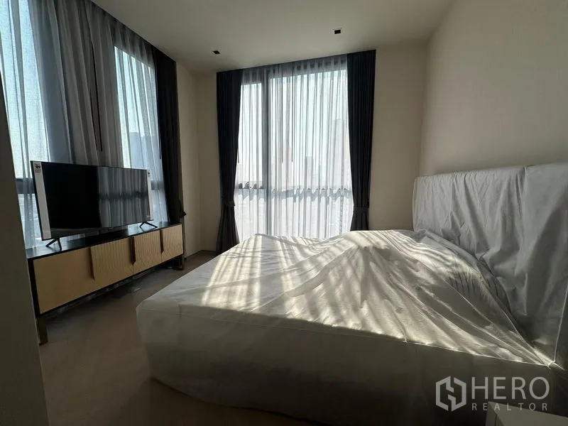 Condominium for rent - Bedroom with double bed, TV stand and wraparound windows with curtains.